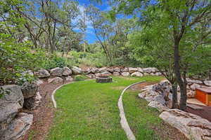 View of green lawn featuring a fire pit
