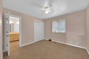 Unfurnished bedroom featuring carpet flooring, a textured ceiling, a closet, and ceiling fan