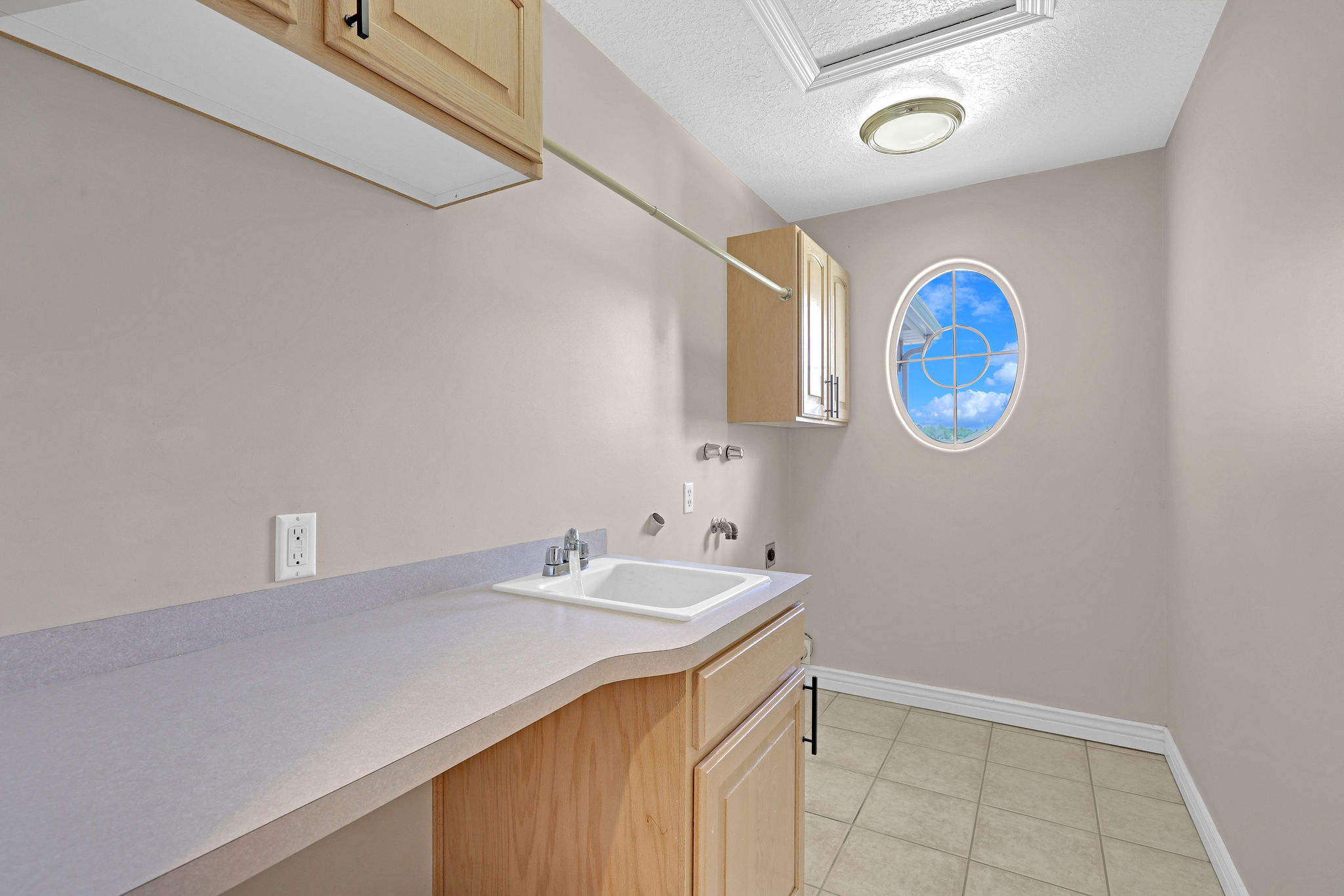 Laundry area with a textured ceiling, electric dryer hookup, cabinet space, light tile patterned floors, and hookup for a washing machine