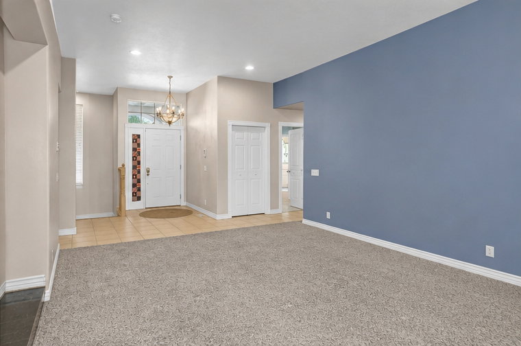 Entryway featuring a white paneled door with sidelight window, transom window, and an overhead chandelier