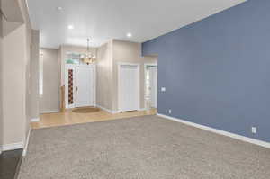 Entryway featuring a white paneled door with sidelight window, transom window, and an overhead chandelier