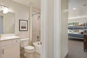 Bathroom with shower / bathtub combination, vanity, ensuite bathroom, light colored carpet, and a textured ceiling