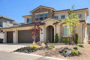 Mediterranean / spanish-style house featuring stone siding, concrete driveway, stucco siding, a tile roof, and an attached garage