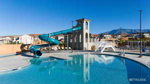 Community pool featuring a water slide, a residential view, a mountain view, and a patio area