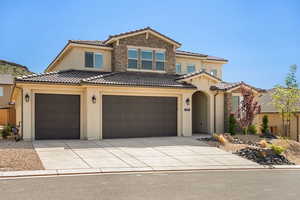 View of front of home with stone siding, stucco siding, concrete driveway, a tile roof, and a garage