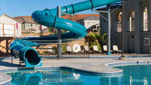 Community pool with a water slide and a patio area