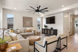 Living room featuring light wood-style flooring, ceiling fan, recessed lighting, and plenty of natural light