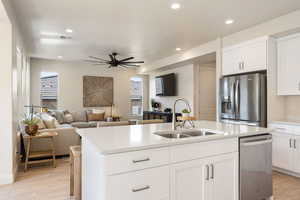 Kitchen featuring stainless steel appliances, white cabinetry, open floor plan, light stone counters, and recessed lighting