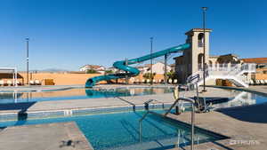Community pool featuring a water slide, a patio, and stairway