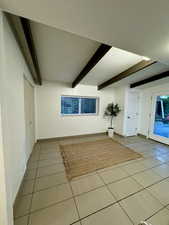 Unfurnished living room with beamed ceiling and tile patterned flooring