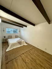 Bedroom featuring beamed ceiling and wood finished floors