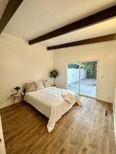 Bedroom featuring wood finished floors, beamed ceiling, and access to outside