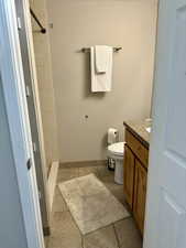 Full bath with tiled shower, vanity, and light tile patterned floors