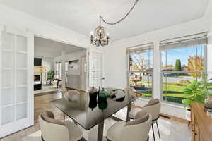 Dining area featuring crown molding, a lit fireplace, light tile patterned floors, and a chandelier