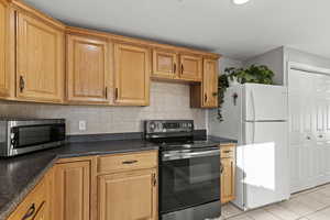 Kitchen featuring appliances with stainless steel finishes, decorative backsplash, and light tile patterned flooring