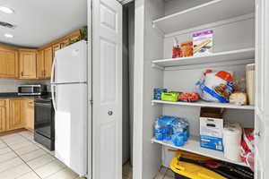 Kitchen with light tile patterned floors, freestanding refrigerator, dark countertops, electric range, and backsplash