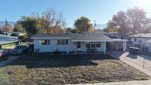 View of front of home featuring concrete driveway, a front lawn, and a carport