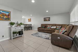 Living room with light tile patterned flooring and recessed lighting
