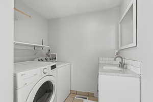 Washroom with light tile patterned flooring, washer and dryer, and cabinet space