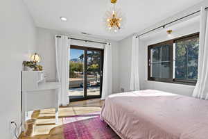Bedroom featuring wood-type flooring, access to exterior, recessed lighting, and a chandelier