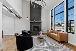 Living room featuring a large fireplace, a high ceiling, wood finished floors, and a chandelier