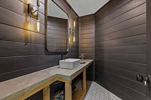 Half bath with vanity and wood walls