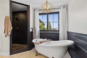 Bathroom featuring a freestanding tub, a shower stall, and a chandelier