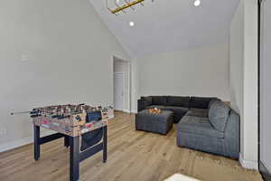 Living area with light wood-type flooring, recessed lighting, and high vaulted ceiling