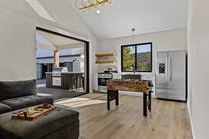Rec room featuring light wood finished floors, high vaulted ceiling, recessed lighting, and a chandelier