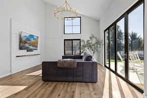 Living room with high vaulted ceiling, wood finished floors, and a chandelier