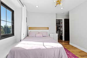 Bedroom featuring wood finished floors, a walk in closet, recessed lighting, and a chandelier