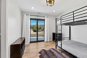 Bedroom featuring light wood-style floors, access to exterior, a textured ceiling, and recessed lighting