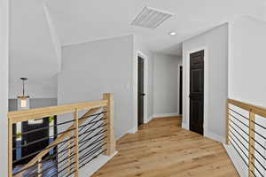 Hall with an upstairs landing, light wood finished floors, recessed lighting, and a textured ceiling
