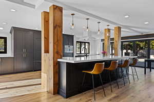 Kitchen with dark cabinetry, decorative light fixtures, light wood-type flooring, plenty of natural light, and recessed lighting