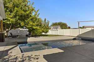 View of swimming pool with a patio, a fenced backyard, and a pool with connected hot tub
