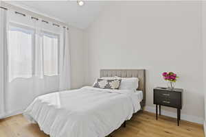 Bedroom with light wood-style flooring and lofted ceiling