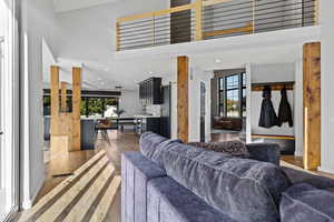 Living area with dark wood-style floors, a high ceiling, and recessed lighting