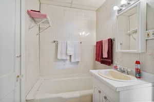 Full bath featuring vanity, tile walls, and a bath
