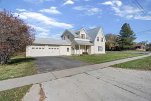 View of front of home with covered porch, asphalt driveway, an attached garage, a front yard, and a metal roof