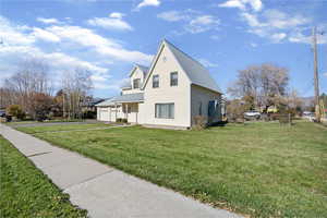 View of side of home featuring a yard, a garage, a porch, driveway, and a metal roof