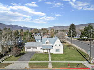 View of front of property featuring a front yard, a residential view, asphalt driveway, a metal roof, and a mountain view