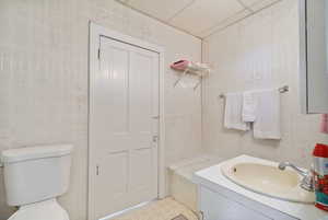 Full bathroom featuring tile walls, vanity, and a bathtub