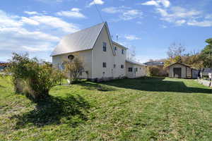 View of side of home with a lawn, a metal roof, and a storage shed