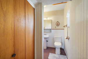 Bathroom featuring wallpapered walls and toilet