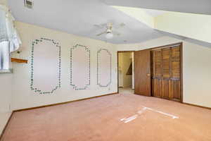 Unfurnished bedroom featuring light colored carpet, a closet, and a ceiling fan