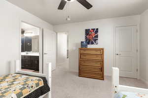 Bedroom featuring light colored carpet, ensuite bathroom, and a ceiling fan