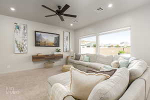 Carpeted living area with ceiling fan and recessed lighting