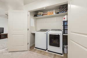 Laundry area upstairs with independent washer and dryer and light wood-style floors