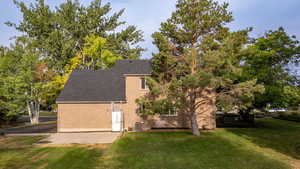 View of side of home with a yard, roof with shingles, and brick siding