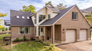 View of front of home featuring a shingled roof, brick siding, and a front lawn